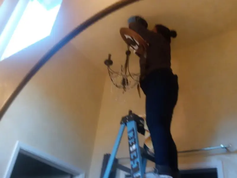 Electrician installing a chandelier in a Stonegate residence